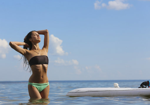 Young beautiful girl is posing on the water of sea near surf des