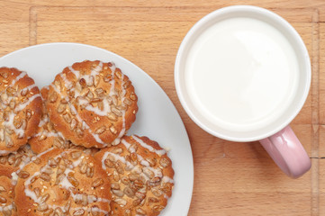 Round cookies with sunflower and sesame seeds, milk in pink mug,