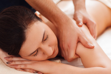 Fototapeta na wymiar Masseur massaging female shoulders closeup. Portrait of young woman enjoying relaxing massage. Beauty, relax, rest, health care, body, pleasure, stress relief concept