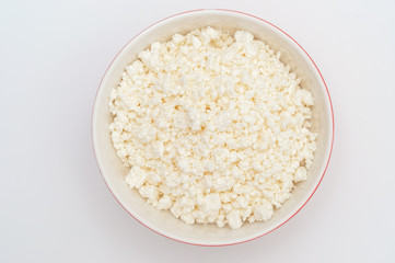 Cottage cheese in red bowl isolated on white, top view. Valuable