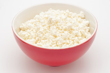 Cottage cheese in red bowl isolated on white. Valuable healthy m