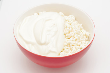 Cottage cheese in red bowl and sour cream isolated on white. Val