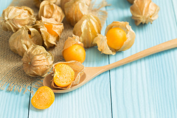 Cape gooseberry in wooden spoon on blue wooden table