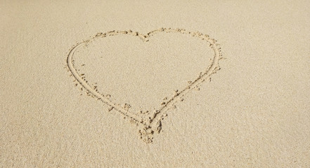 Fototapeta na wymiar Shape of a heart drawn on white sand tropical beach.