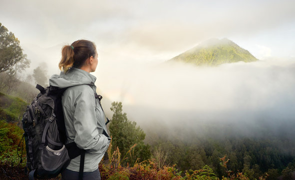 Traveler with backpack on top of a mountain enjoying view volcano.