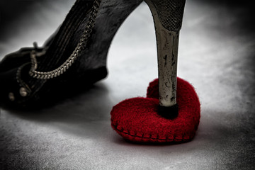 women shoes stomp on broken heart in dark tone., unrequited love., love concept for valentines day.