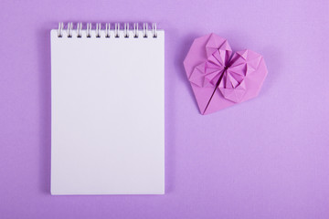 Open notebook with a blank page and origami heart. Valentine paper. Lilac paper heart. St....