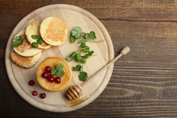Pancakes with berries and a spoon on a wooden tray.