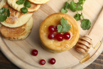 Pancakes with berries and a spoon on a wooden tray.