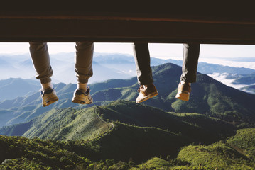 two men legs hanging from the bench against a blue sky and mount