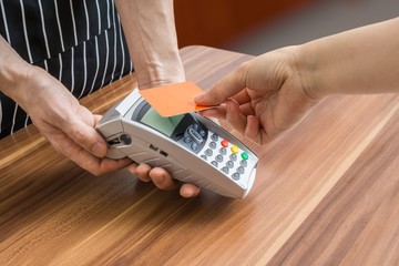 Customer is paying with contactless credit card in shop.