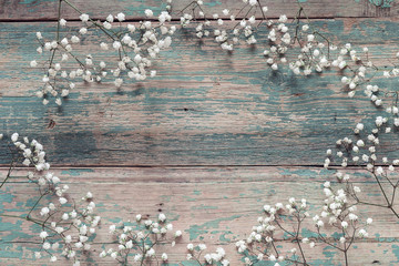 Frame of delicate little white flowers on old blue background fr