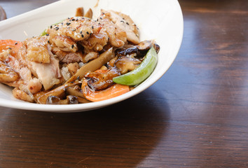 side view of rice and yellow curry chicken with vegetable serve in white bowl on wooden table