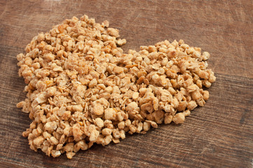 Quick and tasty breakfast granola in a heart shape on wooden board