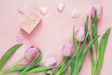 Pink tulips, hearts and gift box on rosy background. Top view wi