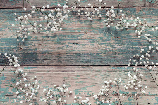 Fototapeta Frame of delicate little white flowers on old blue background fr