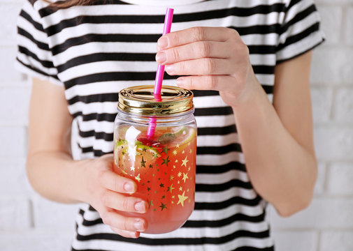 Woman holding fruit lemonade in mason jar, closeup