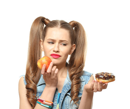 Funny young woman with apple and donut on white background