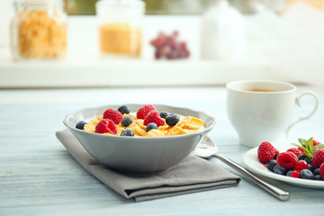 Tasty cornflakes with raspberries and blueberries on table