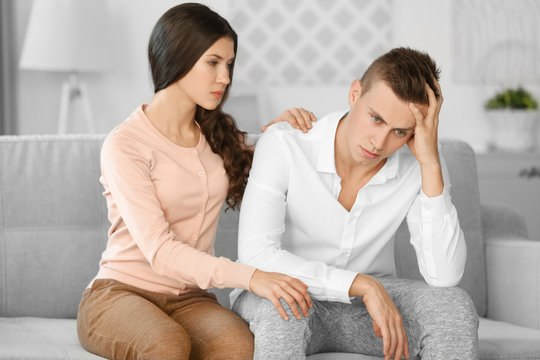 Young depressed man with girlfriend at home