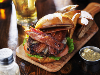bacon cheeseburger on toasted pretzel bun served with fries and beer