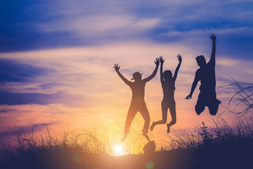 The silhouette of three people jumping with sunset background. f