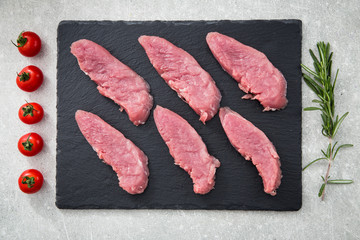raw pork meat on a slate Board, on a stone background