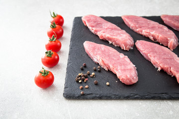 raw pork meat on a slate Board, on a stone background