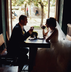 Newlyweds drink cappuccino next to the window in the cafe