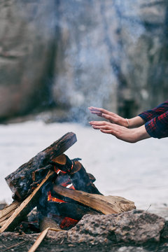 Girl warms hands near a fire in winter