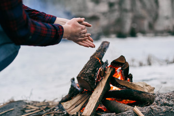 Girl warms hands near a fire in winter