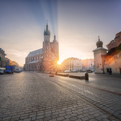 Old town of Krakow with St. Mary's church (Mariacki cathedral) at sunrise, colorful cityscape with rising sun, rays and lens flare, Poland, Europe