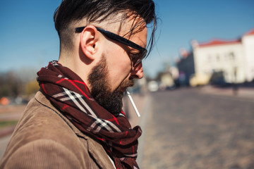 young beard  man posing in the street, cigarette 