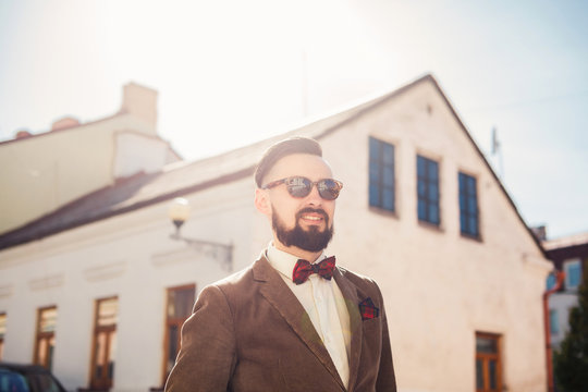 young beard man posing in the street, fashion style, vintage glasses, sunglasses, mustache