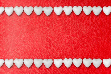 Two rows of white hearts on red leather background