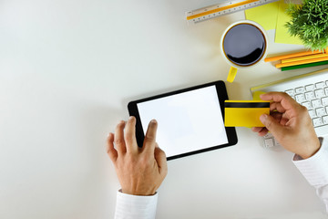 Online payment Concept. Man using credit card and Office desk table with computer, supplies, phone and coffee cup.