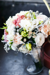 Gorgeous wedding bouquet stands in a bottle on grey table