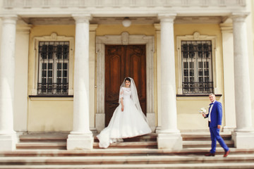 Naklejka premium Groom in blue suit walks to bride holding in his hands wedding b