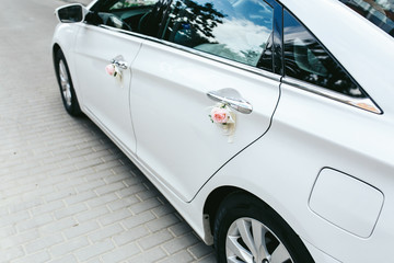 Fototapeta premium White Hyundai with handles decorated with pink and white roses for wedding cortege