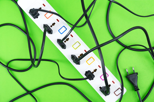 Maximum electrical cords connected electrical power strip or extension block  with messy wires, top view on colorful background, messy electric equipment flat lay concept.