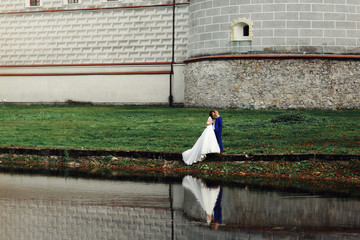 Wedding couple reflects in the lake posing before old white cast