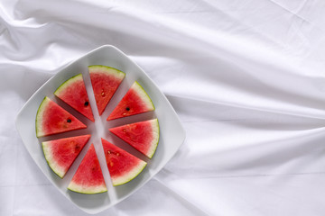 Pieces of ripe watermelon looks like a pizza on plate on the table. Horizontal view from above.