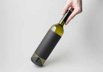 Hand is holding wine bottle on gray background