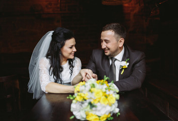 Beautiful newlyweds and a wedding bouquet in the cafe