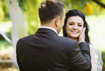 Groom is touching tenderly a face of the bride