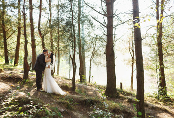 Romantic kiss of the newlyweds with the smoke in the wood