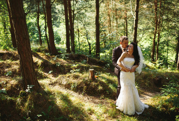 Groom is embracing his beautiful bride in the wood