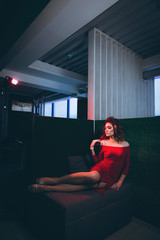 Obraz premium Young beautiful woman in red dress, reclining on a green background