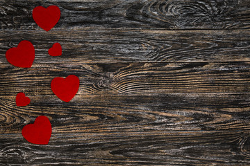 Red hearts on dark wooden background with empty space for text.