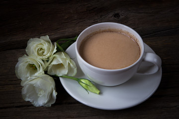 Still life with cup of coffee and flowers Eustoma on wooden back